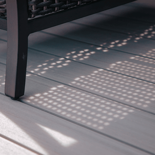 Close-up view of the wooden decking on a porch, focusing on a vertical white post with clean, modern lines against a blurred background of a white railing and water view.