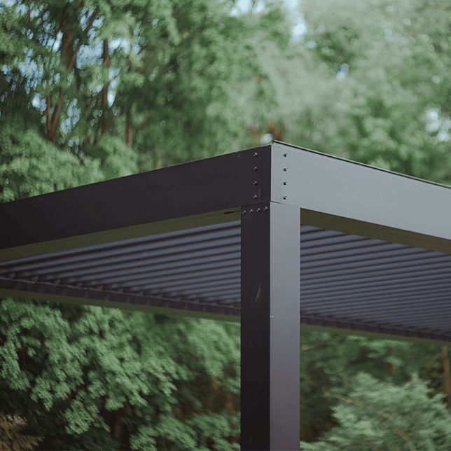Modern outdoor patio area with comfortable seating set under a pergola, complete with a small outdoor fireplace and a backdrop of lush greenery and residential buildings.
