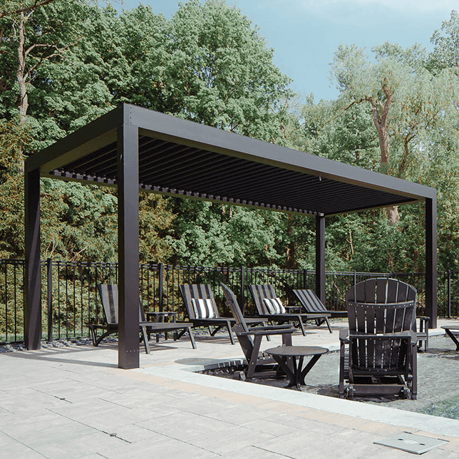 Outdoor swimming pool with clear blue water in the foreground, surrounded by serene patio area with stylish black chairs and a modern pergola, set against a backdrop of lush green trees.