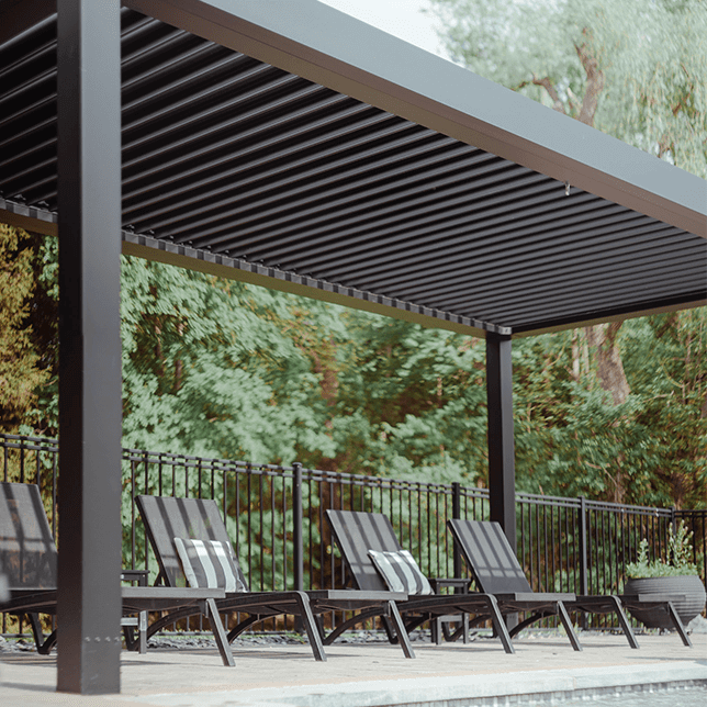 Two dark lounge chairs with striped cushions on a patio overlooking a lush green forest, providing a serene and inviting outdoor relaxation space.