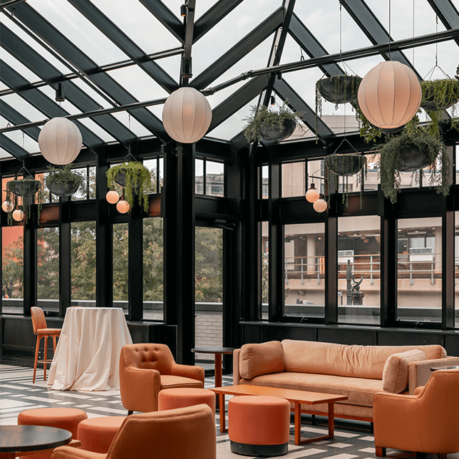 Luxurious outdoor patio area featuring a dining set with rattan chairs under a contemporary pergola, adjacent to an outdoor kitchen and bar, overlooking a scenic pool with a view of distant hills.