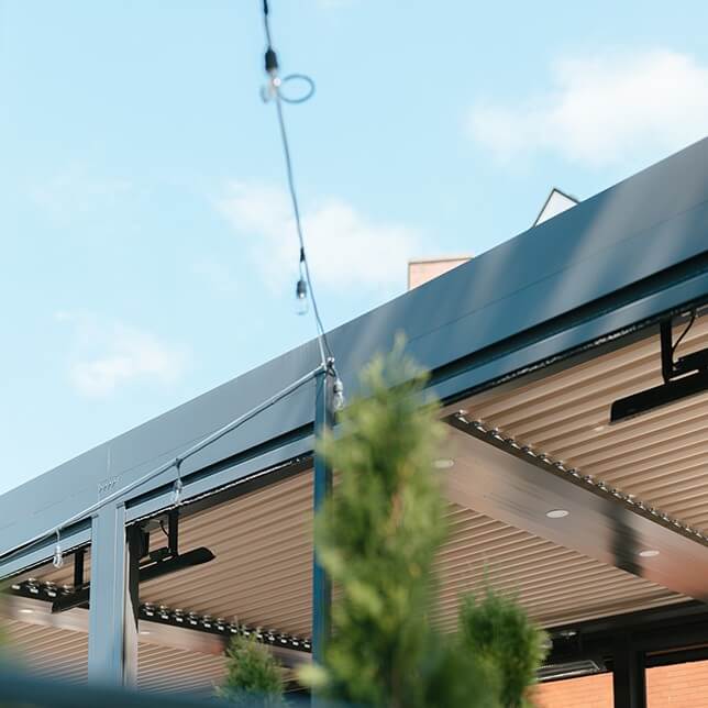 Modern architectural details featuring the corner of a building with a clear blue sky, showcasing a neatly designed overhang with built-in lighting and a stylish blue and beige color scheme.