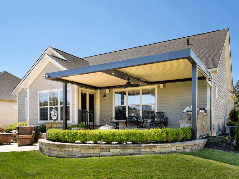 Luxurious suburban home featuring an elegant covered patio with comfortable seating and a neatly landscaped garden, under a clear blue sky. The peaceful exterior design showcases modern outdoor living space, perfect for relaxation and entertainment.