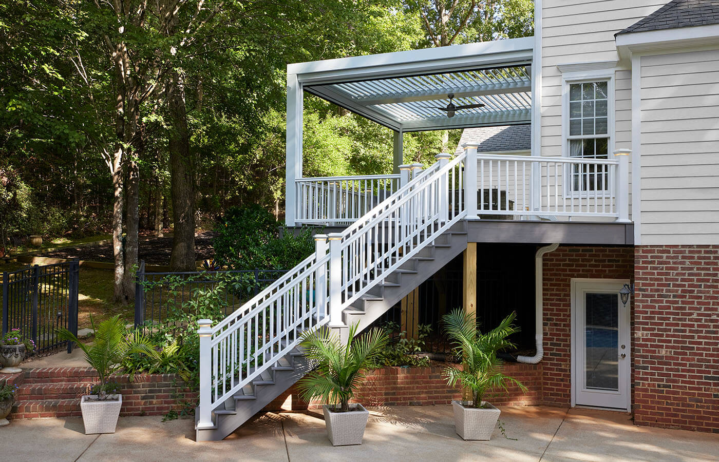 StruXure louvered pergola on TimberTeck composite deck in wooded surrounding