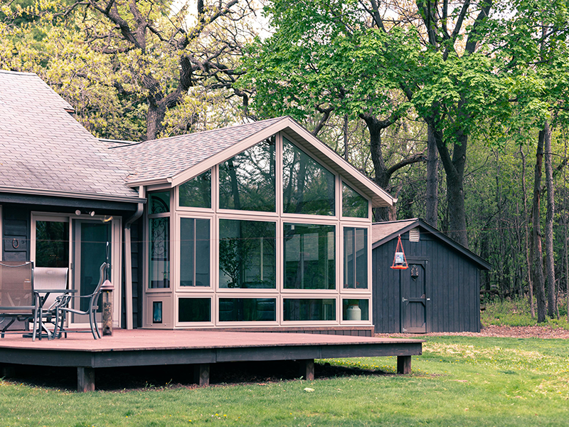 glass sunroom addition in Ann Arbor Michigan surrounded by wooded landscape built by Skyview Detroit