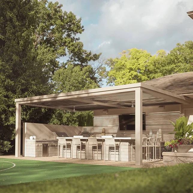 Luxury outdoor kitchen and dining area under a modern pergola, featuring a built-in grill, bar seating, and a lush green backdrop, providing an elegant space for entertaining or relaxing.