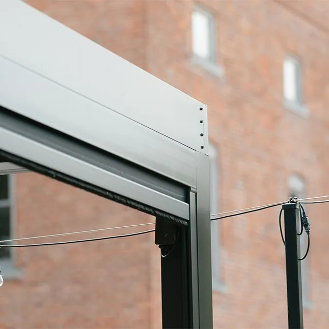 Close-up view of a modern automatic sliding door mechanism with a grey frame, installed at the entrance of a brick building, highlighting its sleek design and compact control boxes.